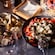 A bowl of feta cheese, tomatoes and cucumbers next to a plate of cheese and meat and a wicker basket with strawberries and blueberries